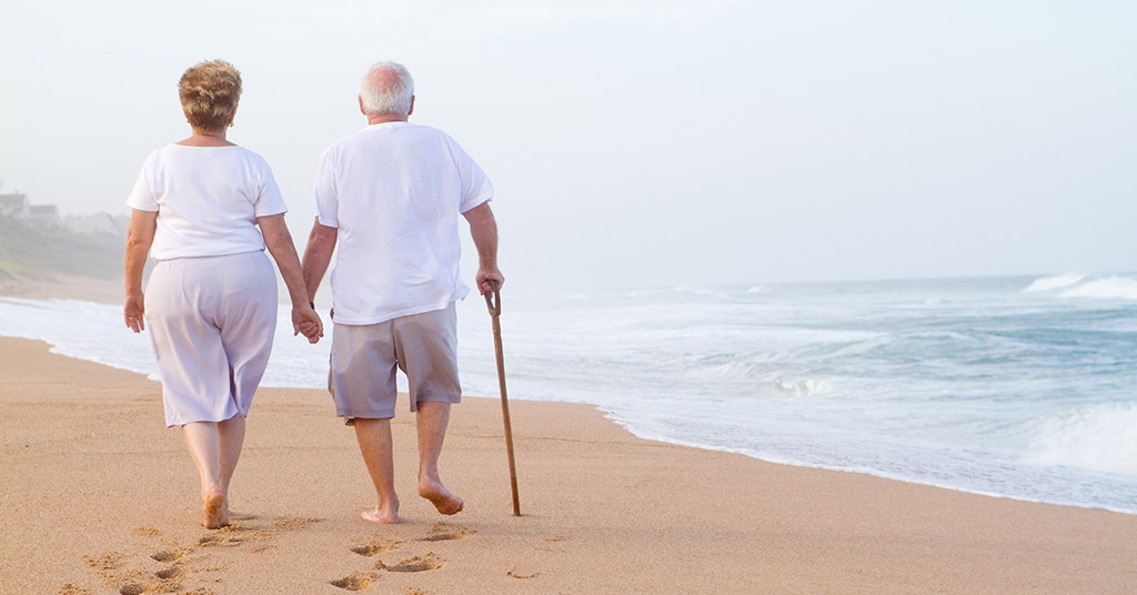 elderly couple walking on the beach